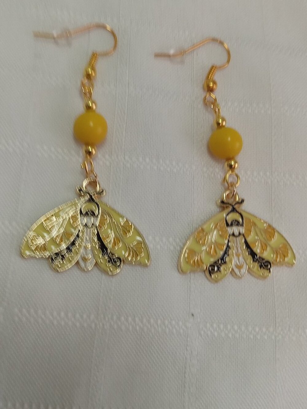 Handmade gold-colored earrings with multicolored enameled butterflies and beads